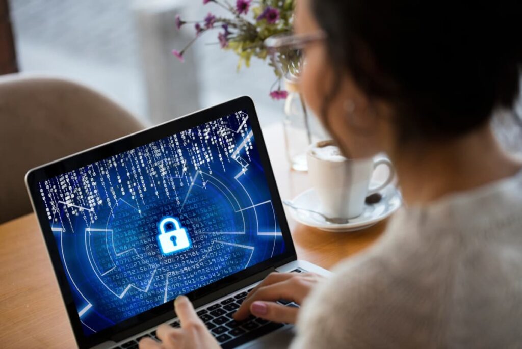 A woman with a laptop displaying a symbol of cybersecurity