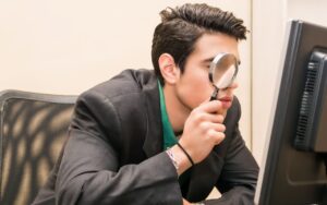 A person using a magnifying glass on a monitor display