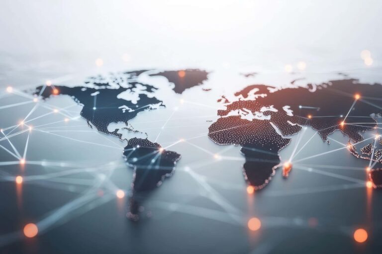 A high-angle, close-up, and blurry photograph shows a dark, three-dimensional world map with glowing white dots and interconnected lines representing a global network.