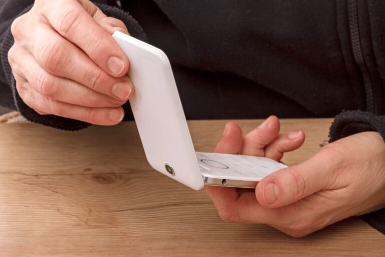 A person holding a clamshell mobile phone.