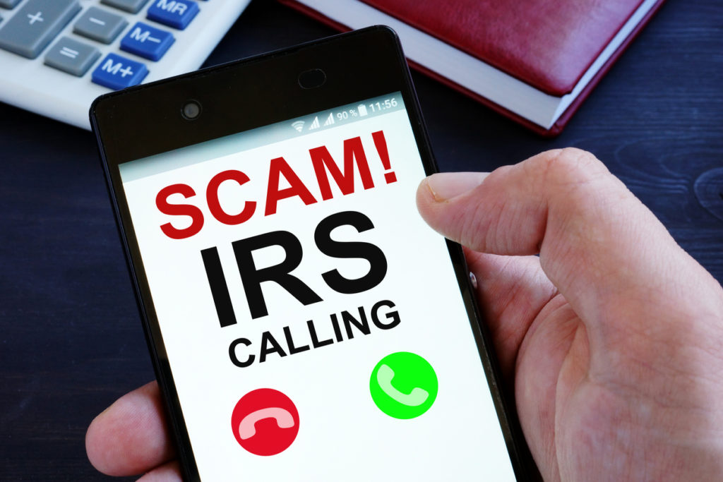 Hand is holding phone with irs scam calls.