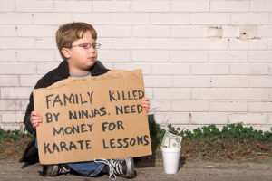 Boy holding sign that reads: Family killed by ninjas. Need money for karate lessons.