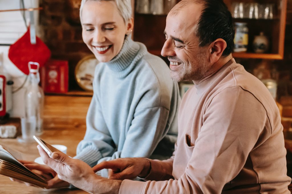 Joyful couple smiling and using tablet at home.