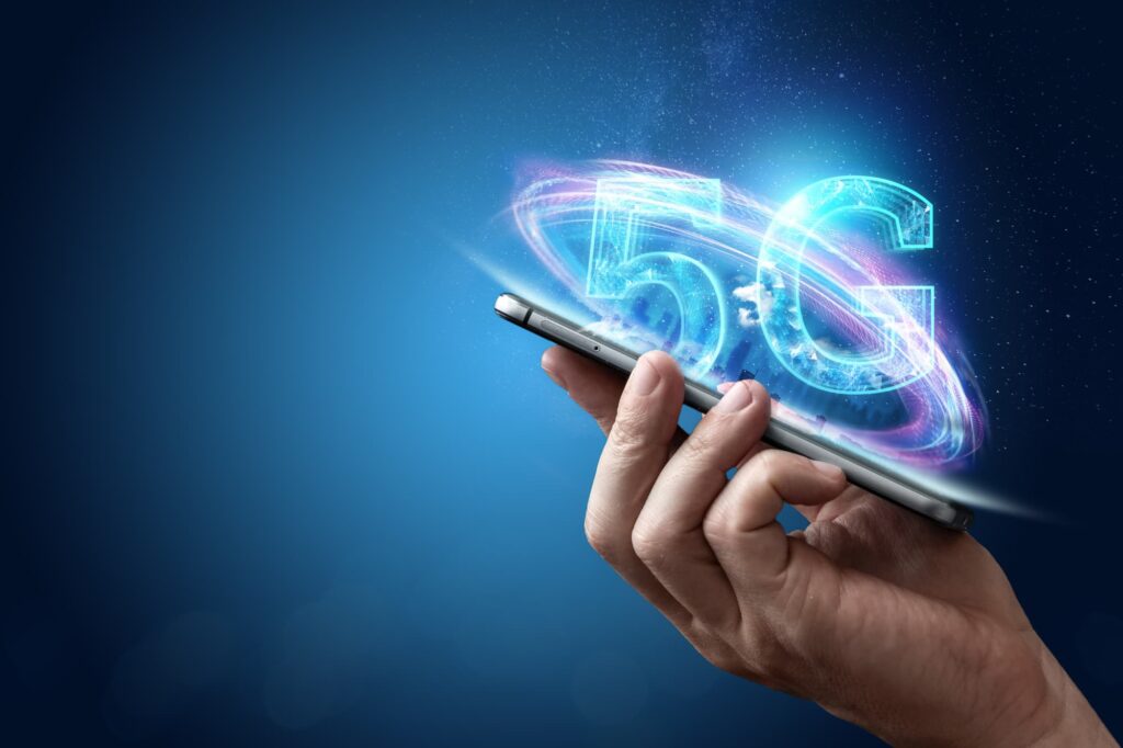 Hand holding a smartphone with a glowing 5G hologram, symbolizing modern network technology and cybersecurity.
