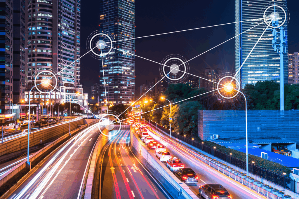 A nighttime cityscape with connected digital nodes over roads and buildings, illustrating the need to build smart city systems securely from the ground up.