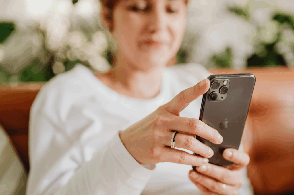 A woman using her iOS smartphone, focused on the screen while holding it with both hands.