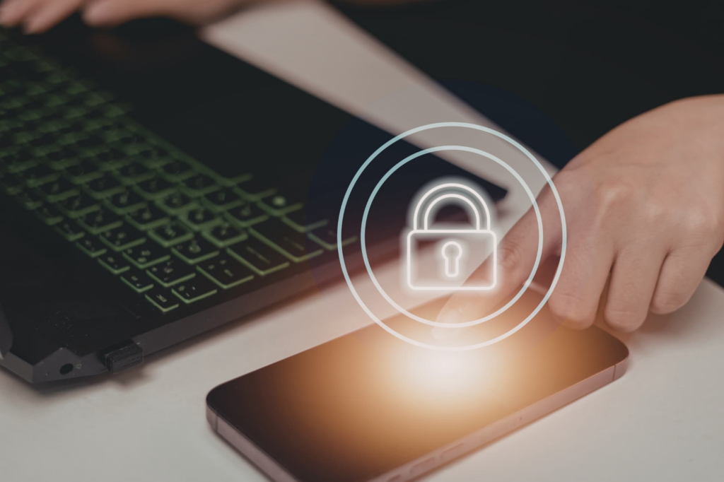 Person using a smartphone and laptop with a digital lock icon overlay, symbolizing stronger privacy settings and protecting personal information online from catfishing or scams.