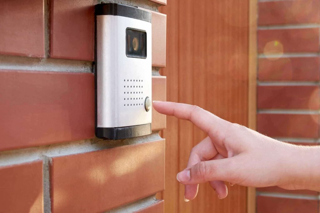 Woman pressing a smart video doorbell button with built-in camera and intercom system