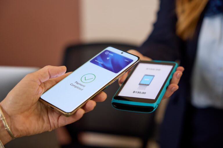 Person using a smartphone to make a contactless NFC payment at a checkout terminal